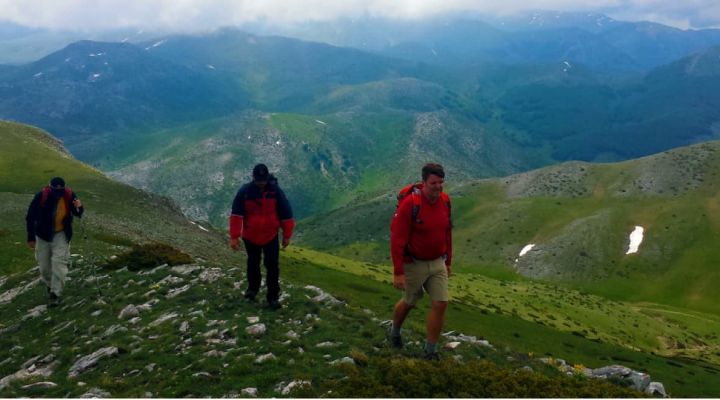 a group of 3 hikers making their way across a green mountain trail in North Macedonia