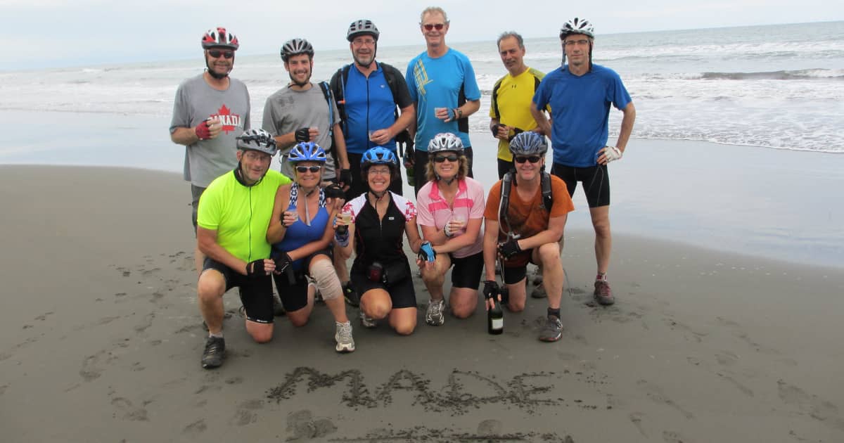 group of travelers with celebrating on the beach with "I made it" written in the sand