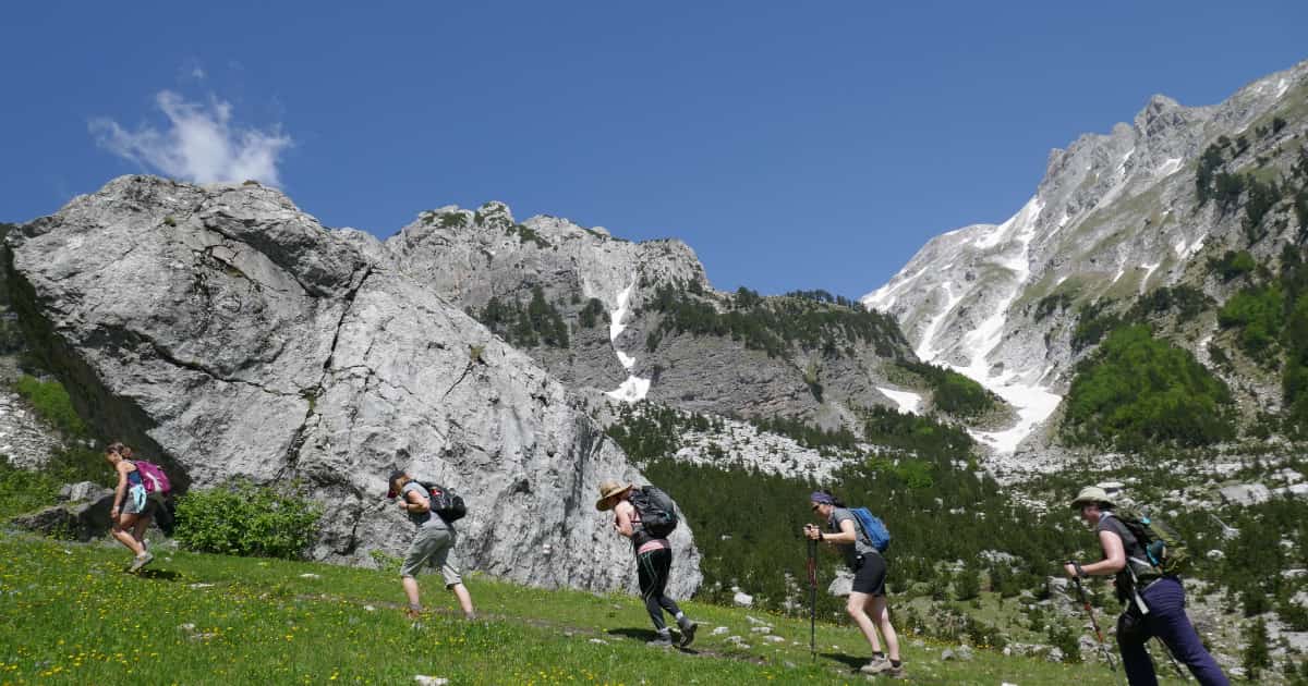 group of travelers hiking up a mountainside 