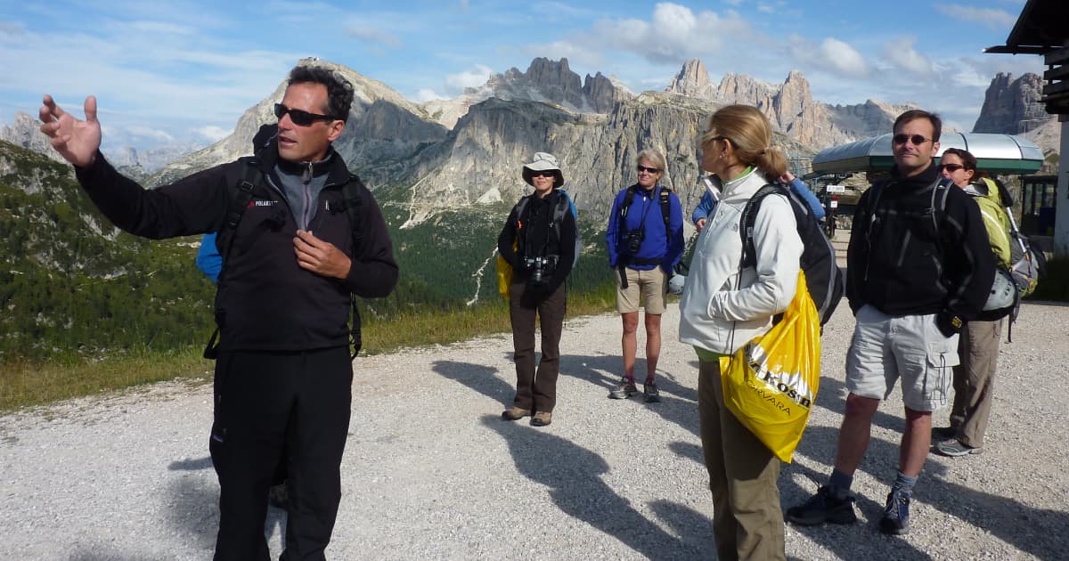 a group of travelers preparing for a hike with the group leader pointing where they should head to first