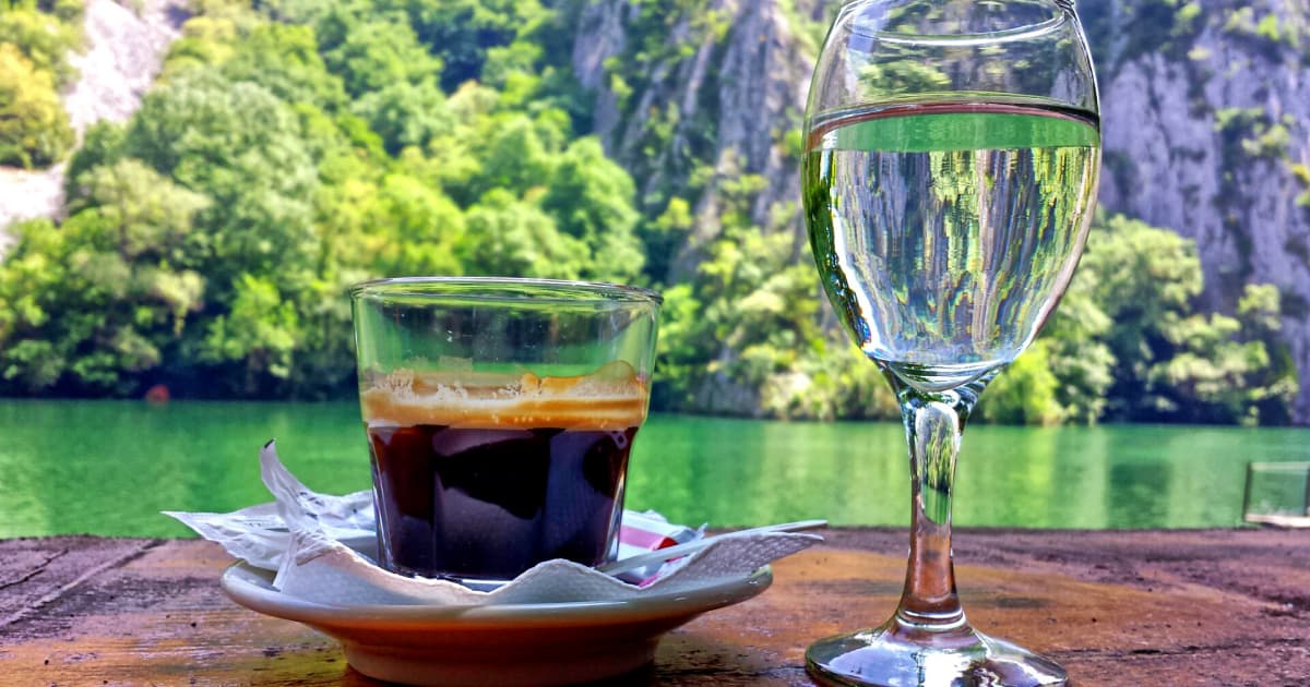 cup of coffee and a glass of water in front of a scenic forest view in costa rica