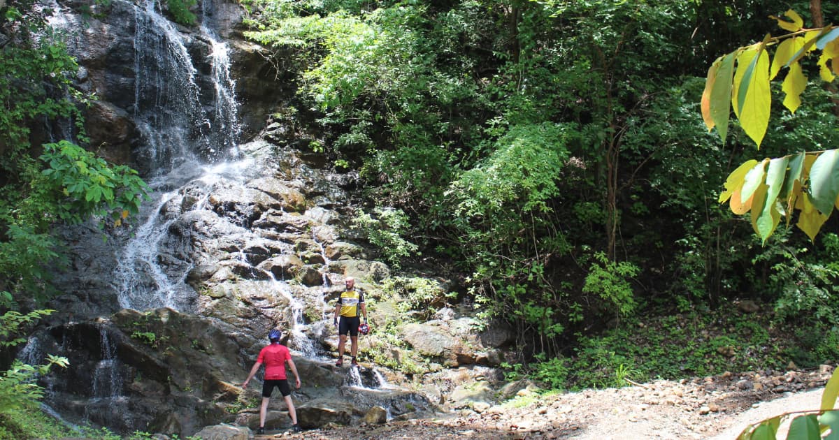 2 hikers standing under a waterfall on a costa rica hiking trail