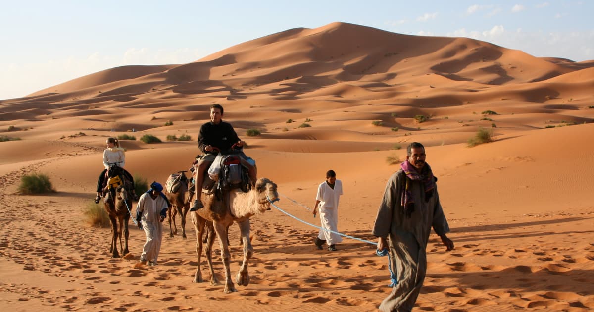 Travelers riding camels through a desert