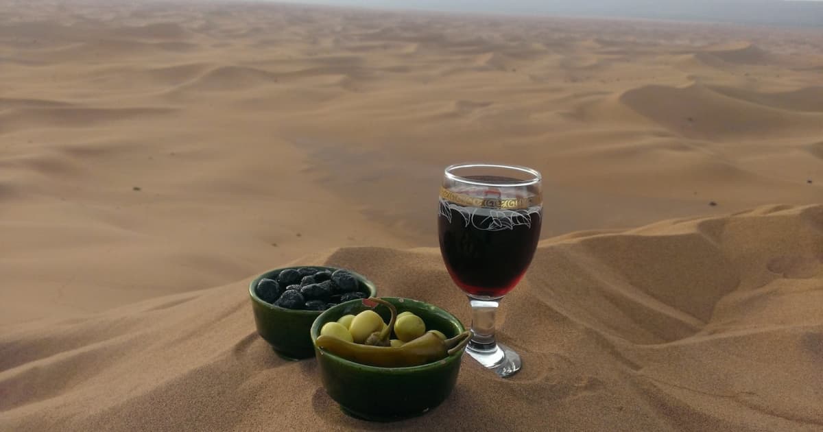 Glass of wine and olives on a sand dune