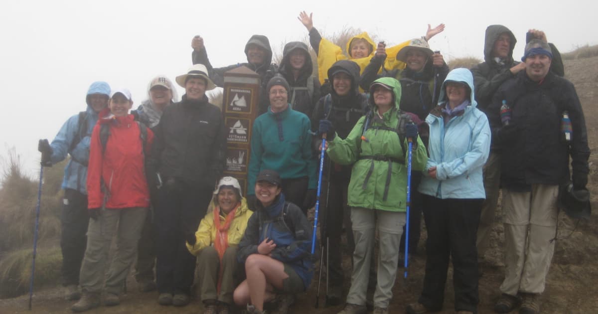 A group of hikers at the top of Machu Picchu on a rainy day, with all hikers wearing rain jackets but looking excited they have completed the hike
