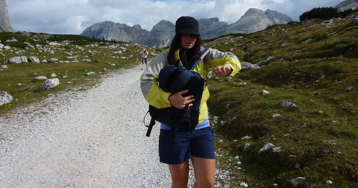 A female hiker on a trail checking the time on her wrist watch