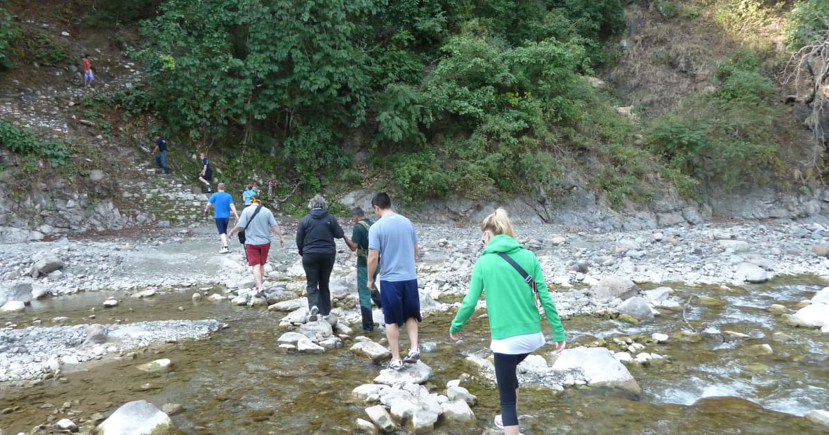 hikers using stones to cross a river