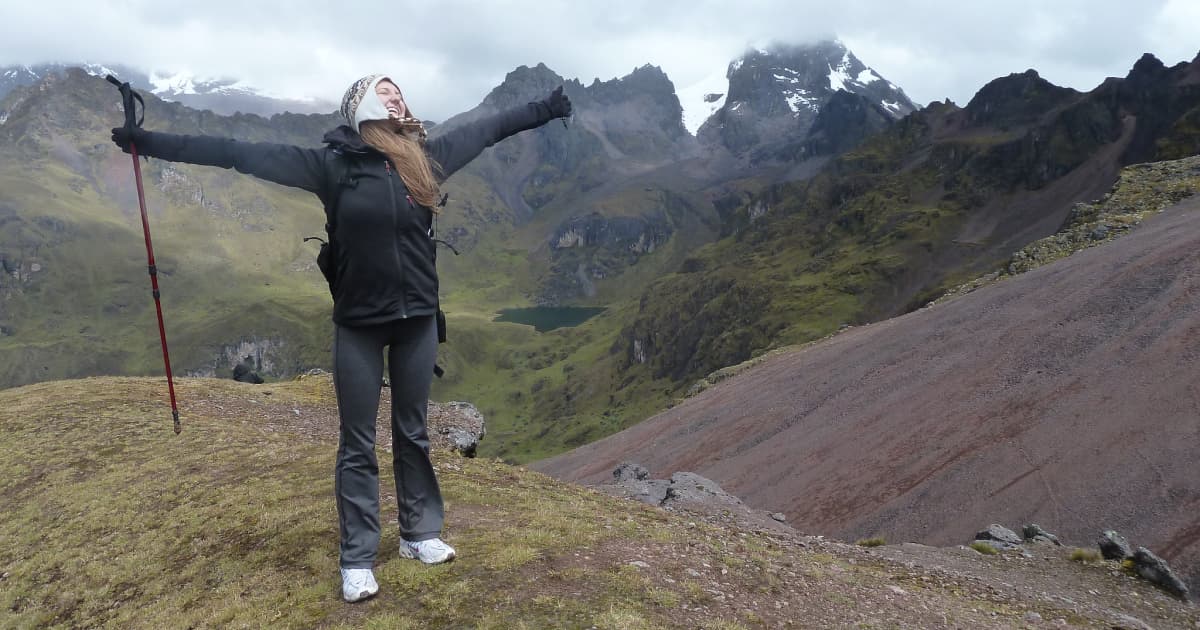 Traveler with arms raised after completing a hike to the top of a mountain