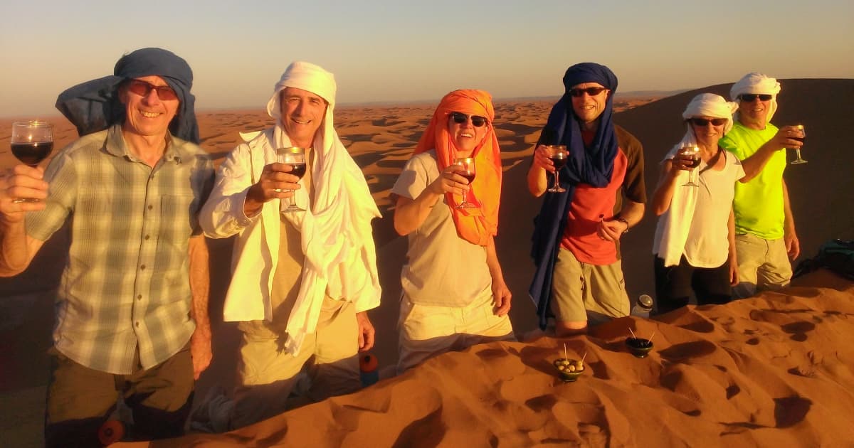 A group of hikers enjoying wine and cheese on the dunes of the Moroccan desert