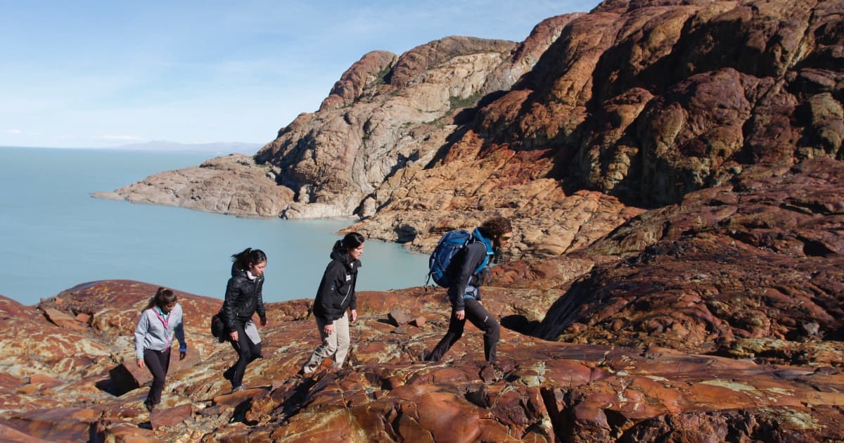 Group of four hikers climbing a steep rocky mountain