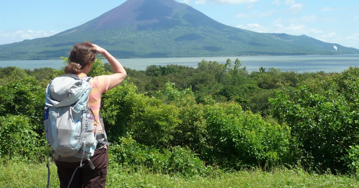 Traveler overlooking a grassy landscape and lake from a hiking trail