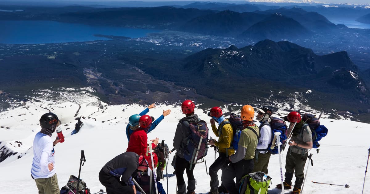 Trekking group sorting their gear on top of a snow capped mountain