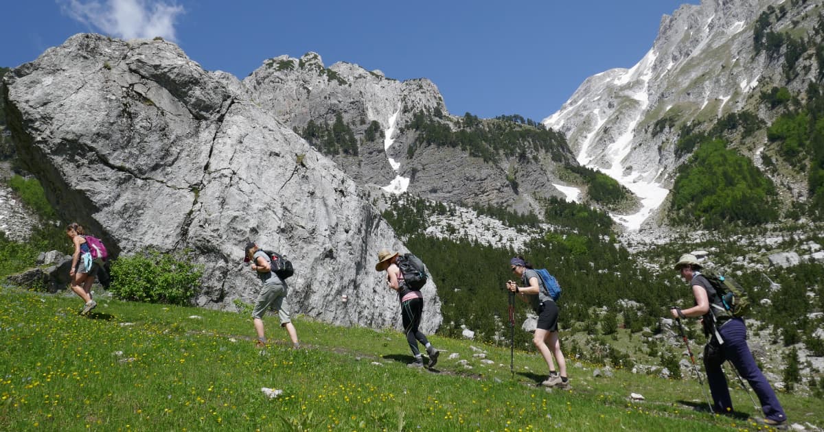 A group of trekkers walking up a steep slope of the albanian alps