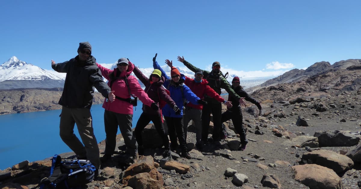 group of hikers posing with arms outstretched on a hiking trail