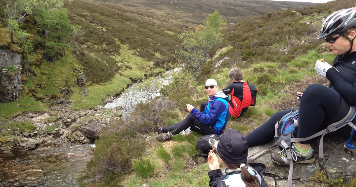 a group of hikers stopped on the side of a trail to eat packed snacks