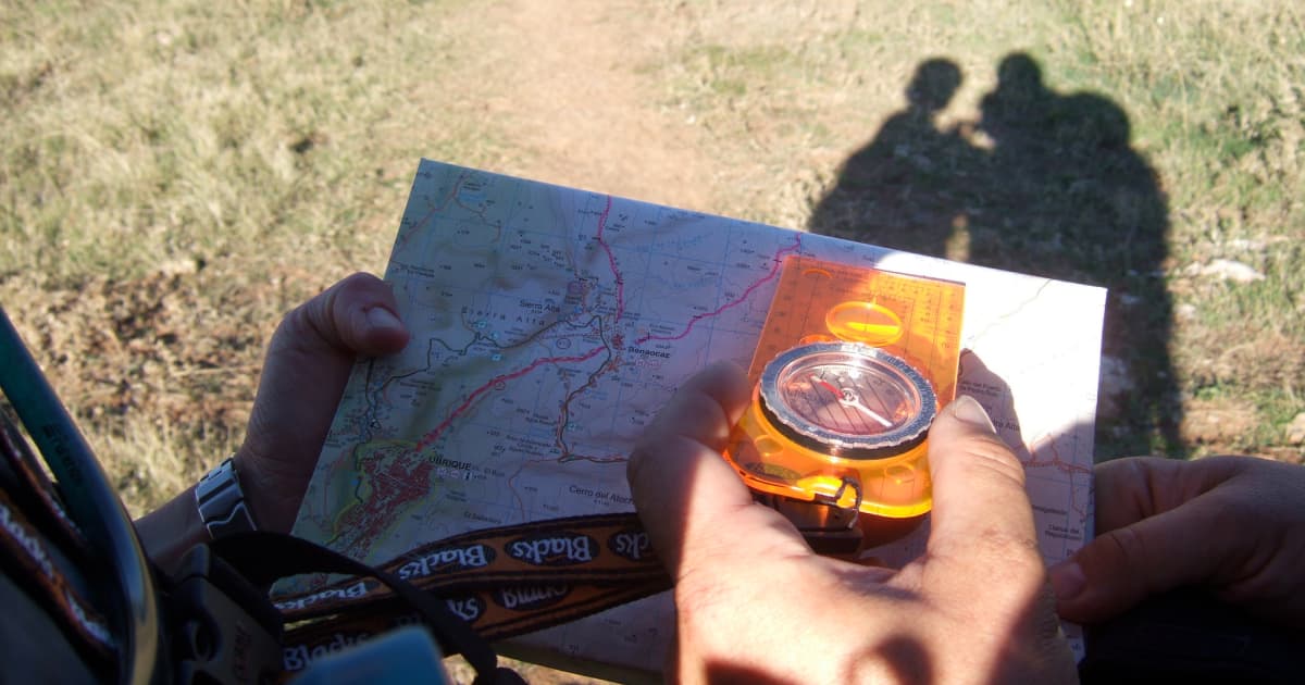 A hiker holding a compass over a map