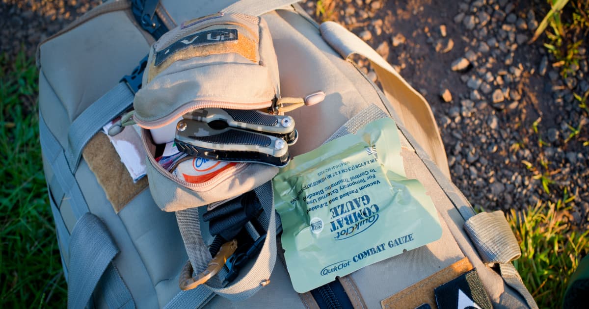 a basic first aid kit on top of a grey hiking bag on the ground