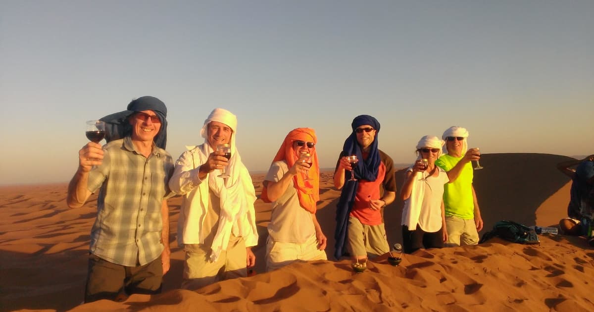 5 travelers enjoying a glass of wine at the Sahara desert 