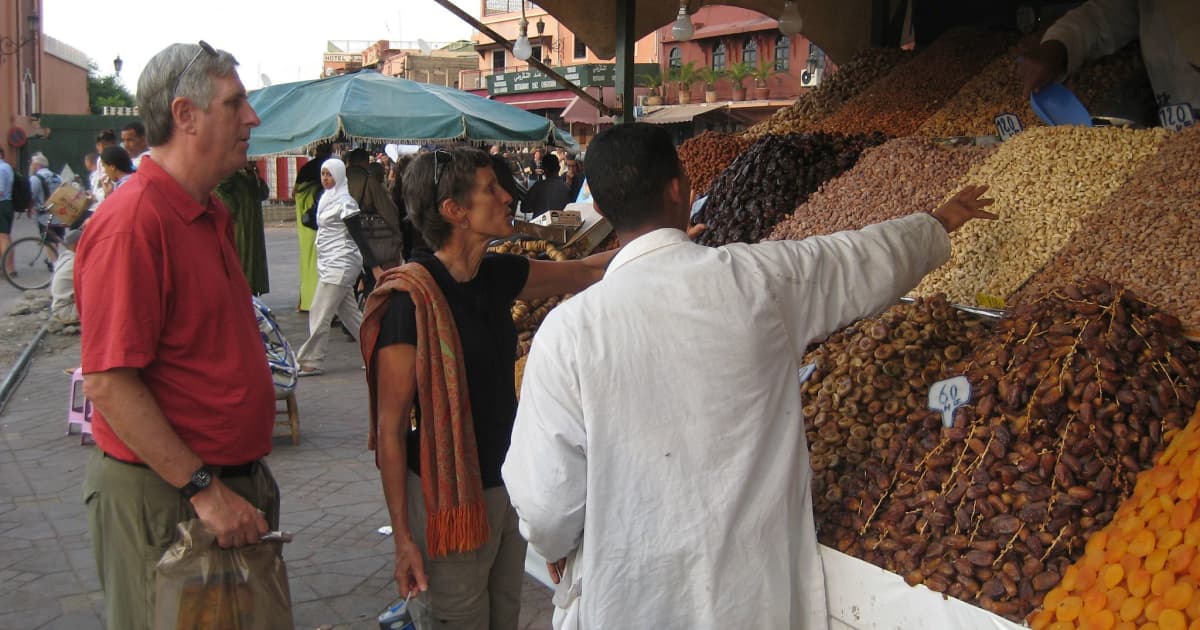 A tourist getting shown around a food stall at a moroccan bazaar