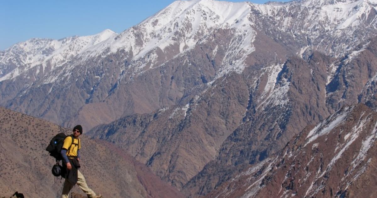 A hiker walking to the backdrop of the snowcapped high atlas mountain range