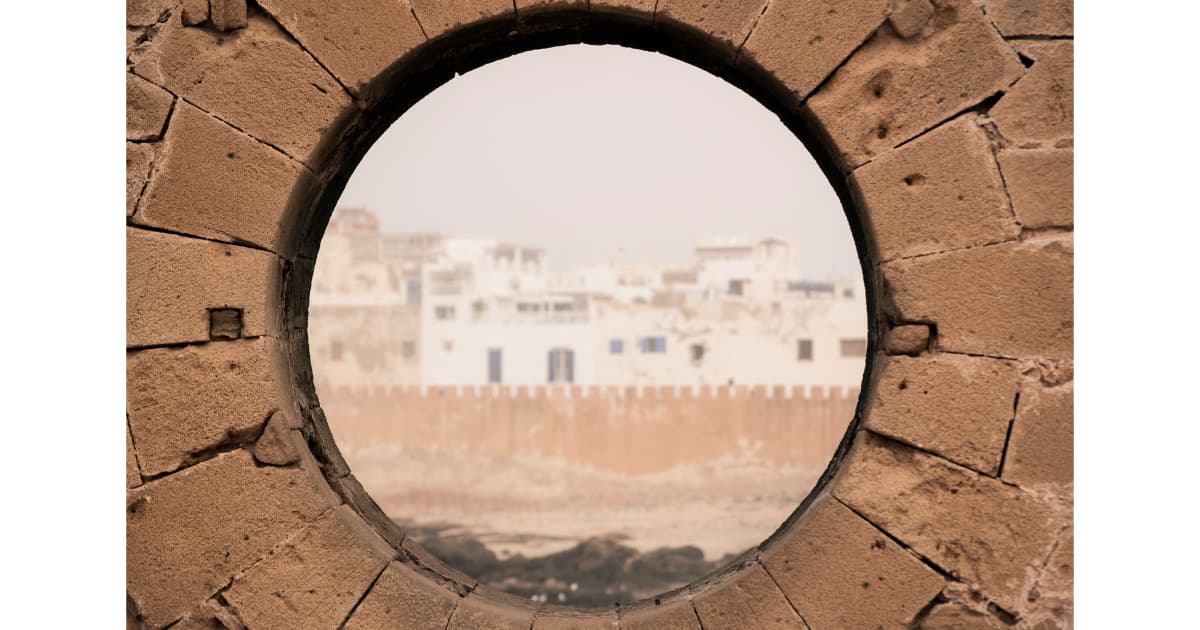 looking through a circular hole in a wall at a Moroccan village