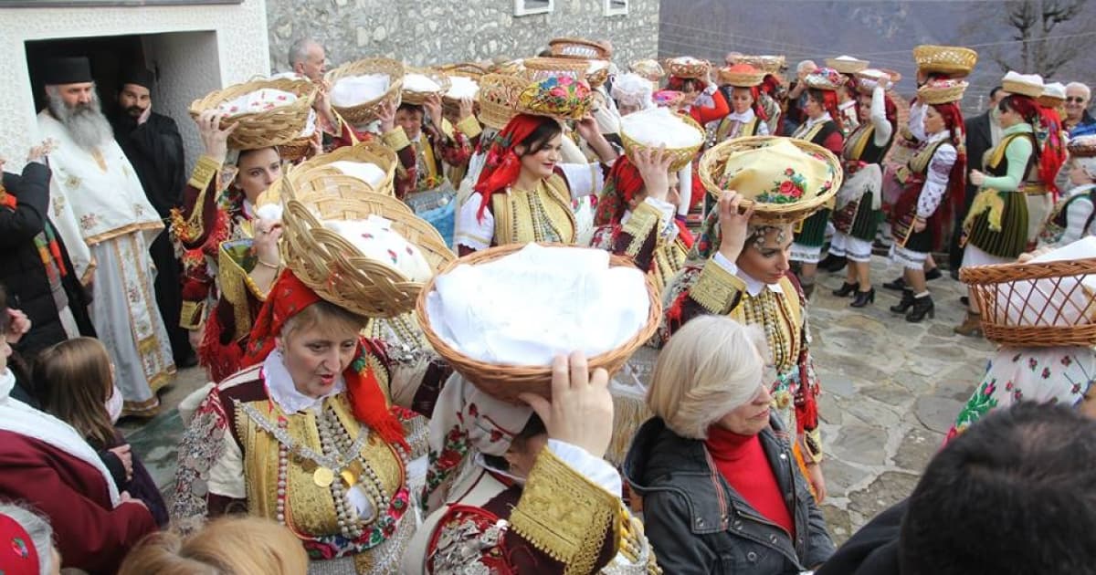 a festival at north macedonia with all the locals dressed in white shirts holding platters in bowls over their heads