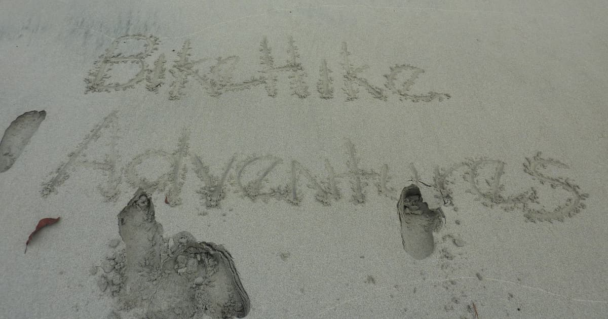 bikehike adventures written into sand on a beach