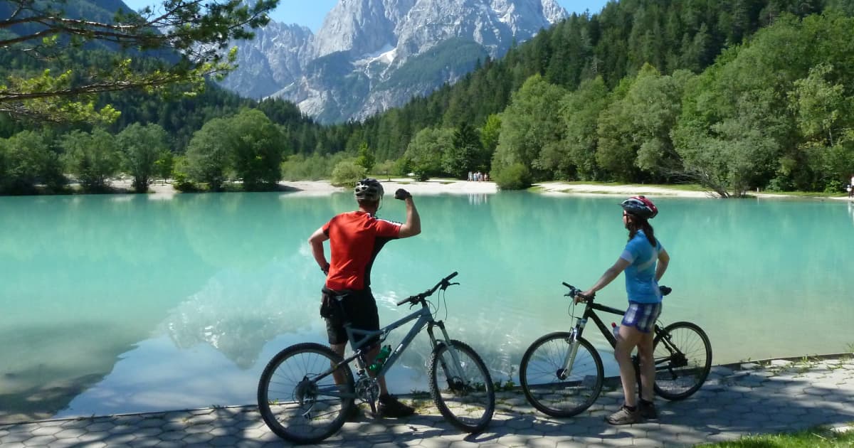 cyclists stopping in front of a lake to admire the view of the julian alps in slovenia