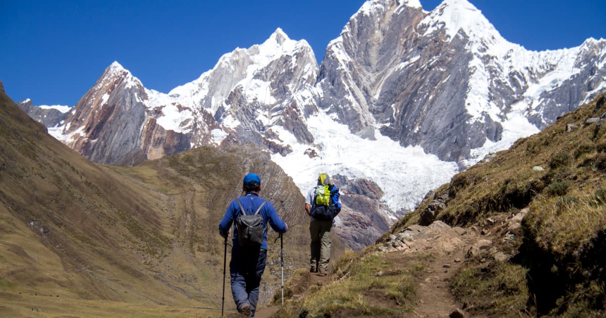 2 hikers walking towards a snow capped distant mountain