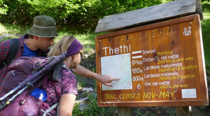 2 fully geared hikers checking out a map on a trail notice board